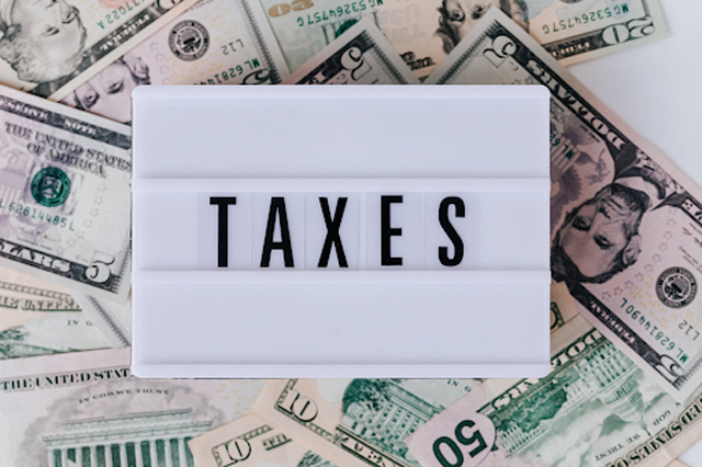 Once you earn, you are now responsible for paying your taxes. “Pile of American banknotes and retro light box,” by “Karolina Grabowska” license under “Pexels.”